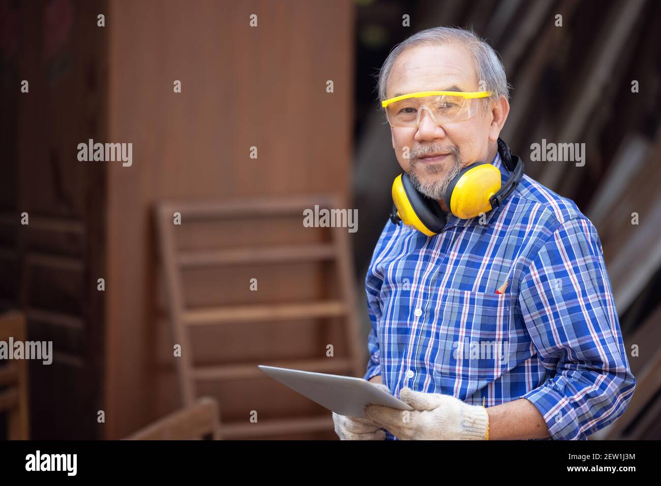 Male carpenter in a construction workshop, using a digital tablet Stock Photo