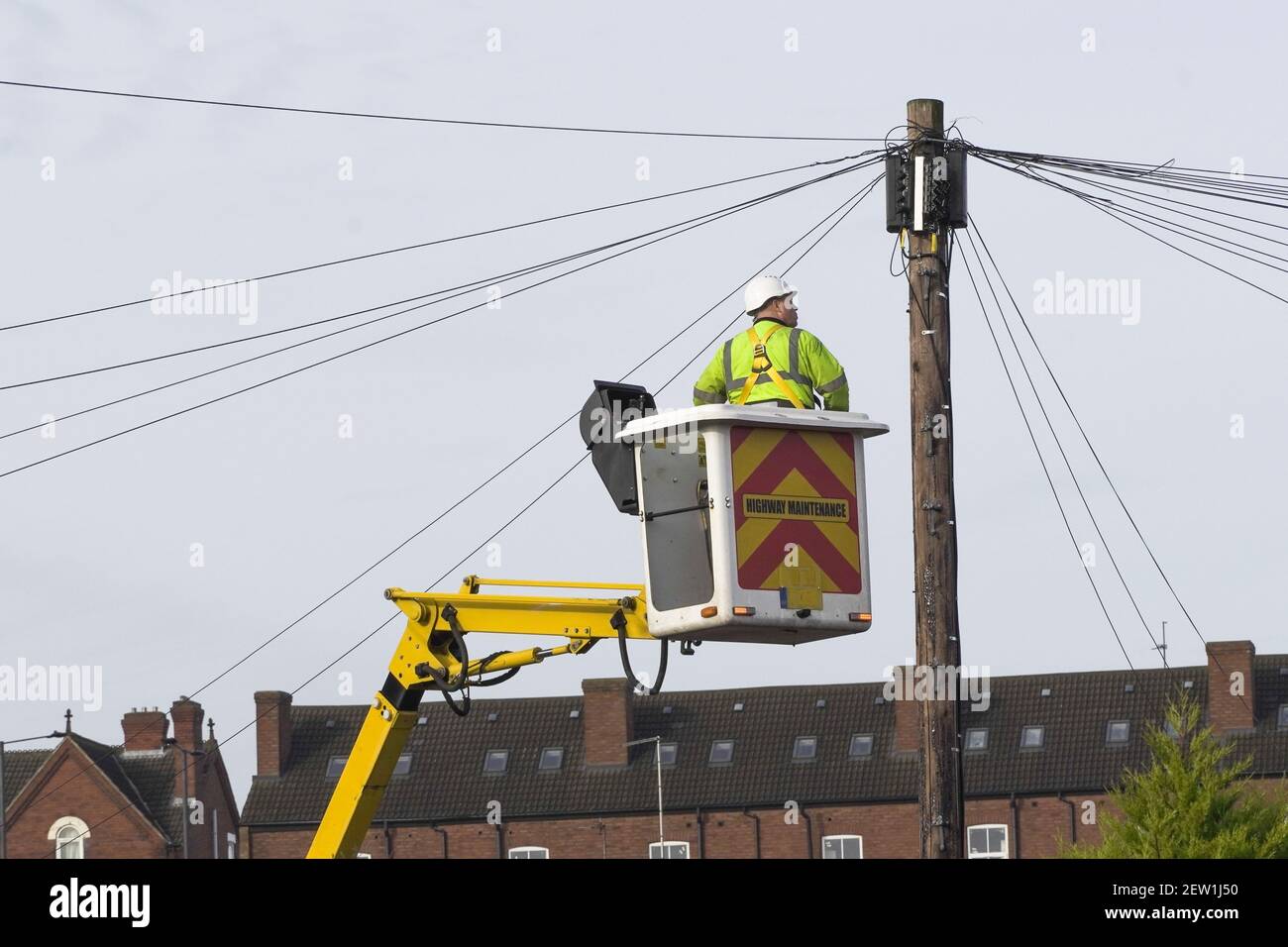 A telecomms power engineer working at height on a lift platform to gain access to a telegraph pole Stock Photo