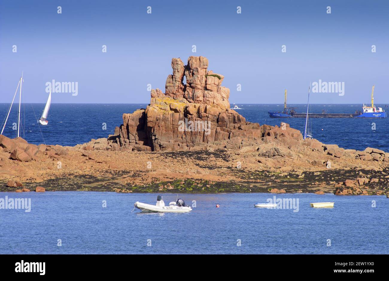 France, Côtes-d'Armor (22), île de Bréhat, barge et voilier derrière les rochers découpés du sud de l'île, a l'entrée du Port-Clos Stock Photo