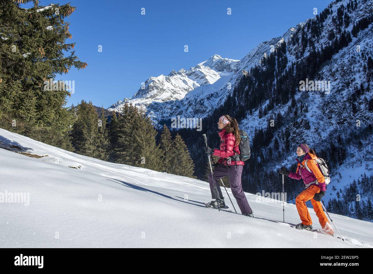 France, Haute Savoie, Mont Blanc massif, Les Contamines Montjoie, two young  women hiking with snowshoes in the Rollaz valley in the nature reserve, and  the aiguille de la Berangere Stock Photo -