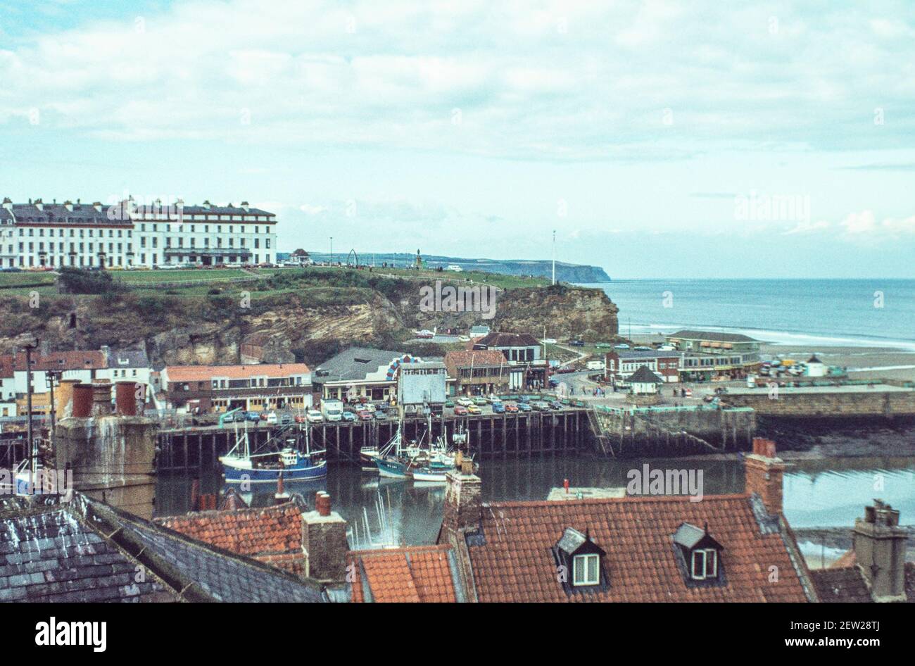 1978 - Whitby Yorkshire -  Whitby west cliff and New town above the harbour with fishing boats moored at the quayside and fish dock Whitby North Yorkshire England UK GB Europe Stock Photo