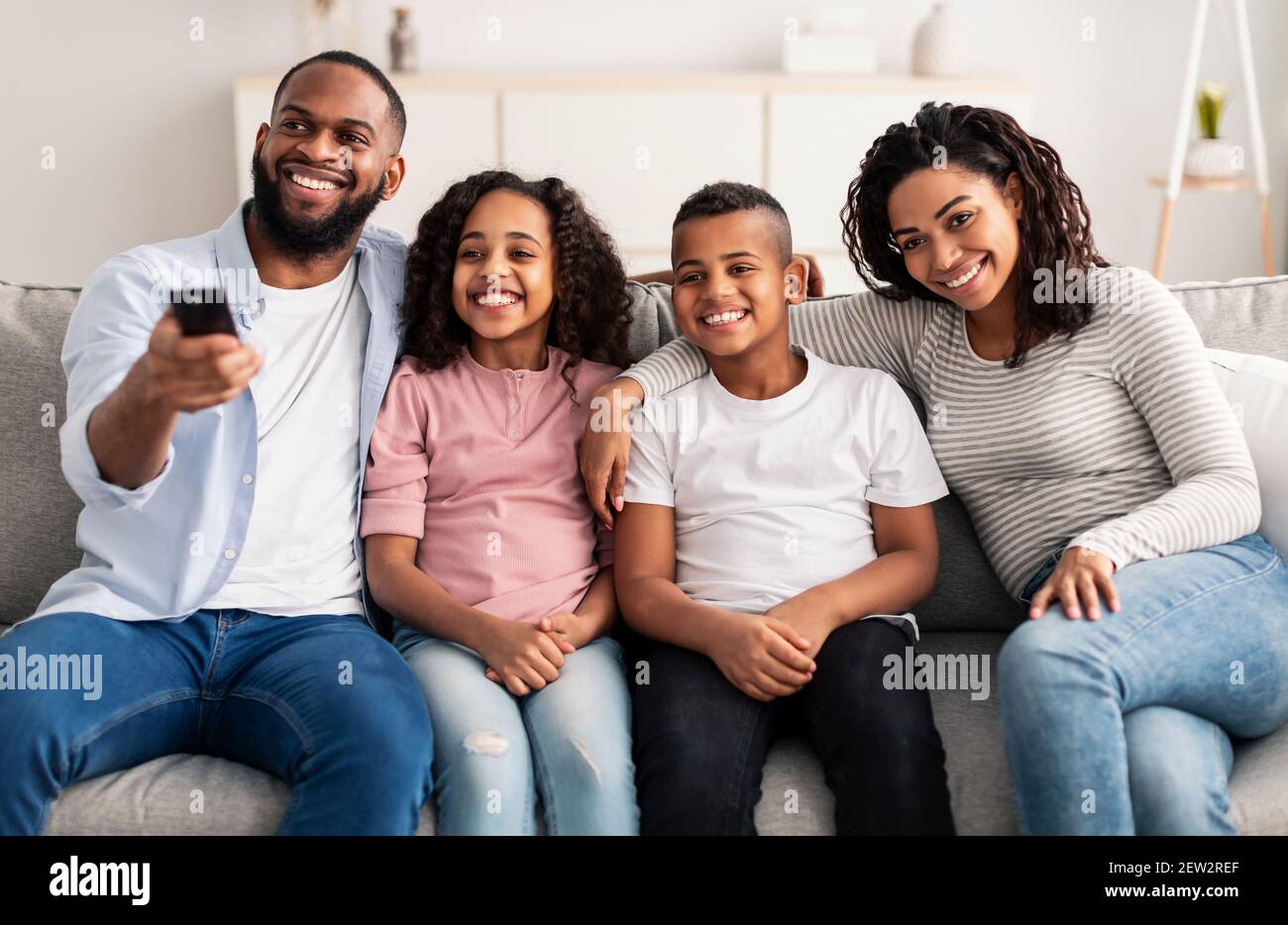 Happy young family watching television sitting on sofa Stock Photo