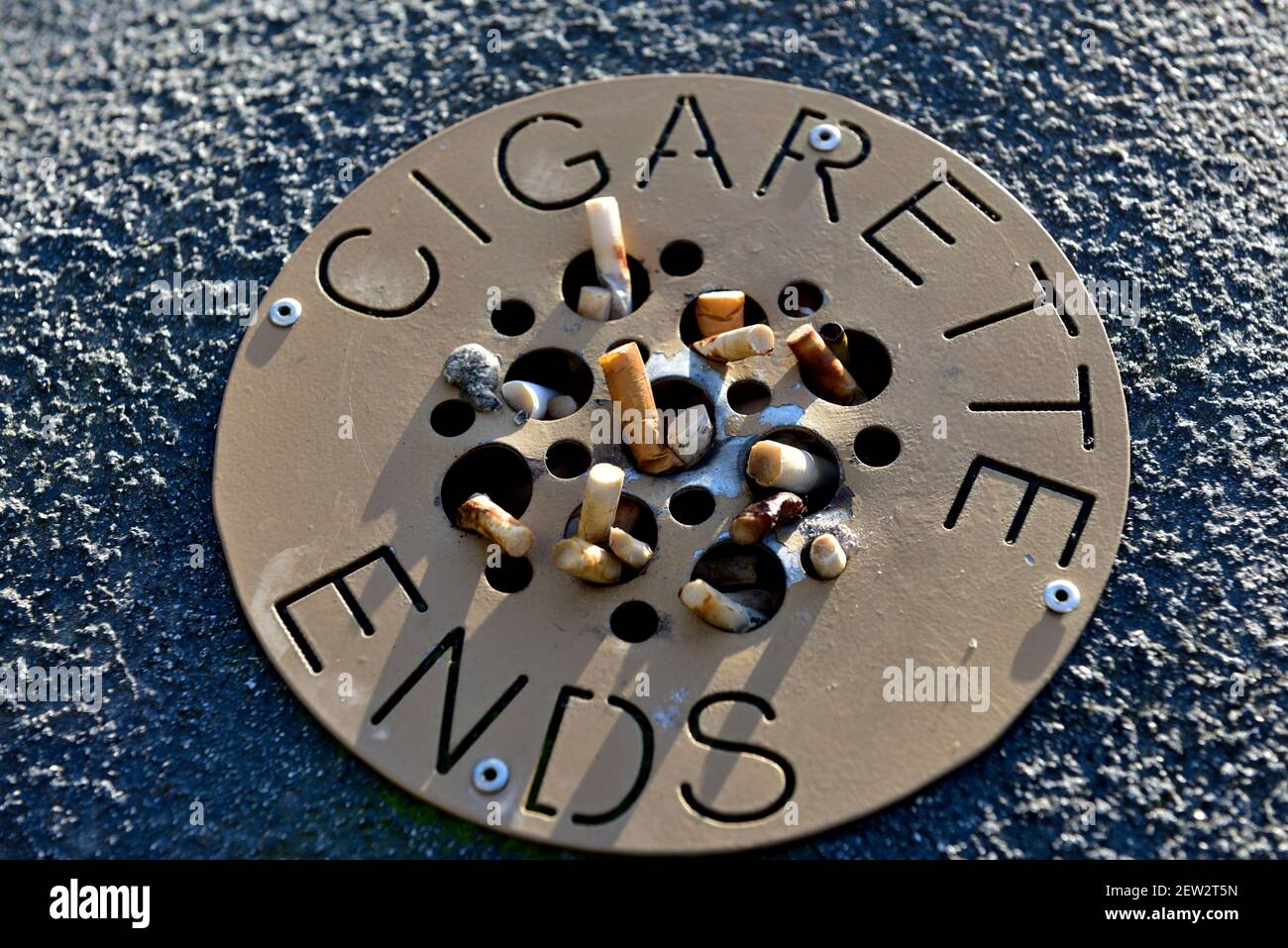 Cigarette ends in public ashtray Stock Photo