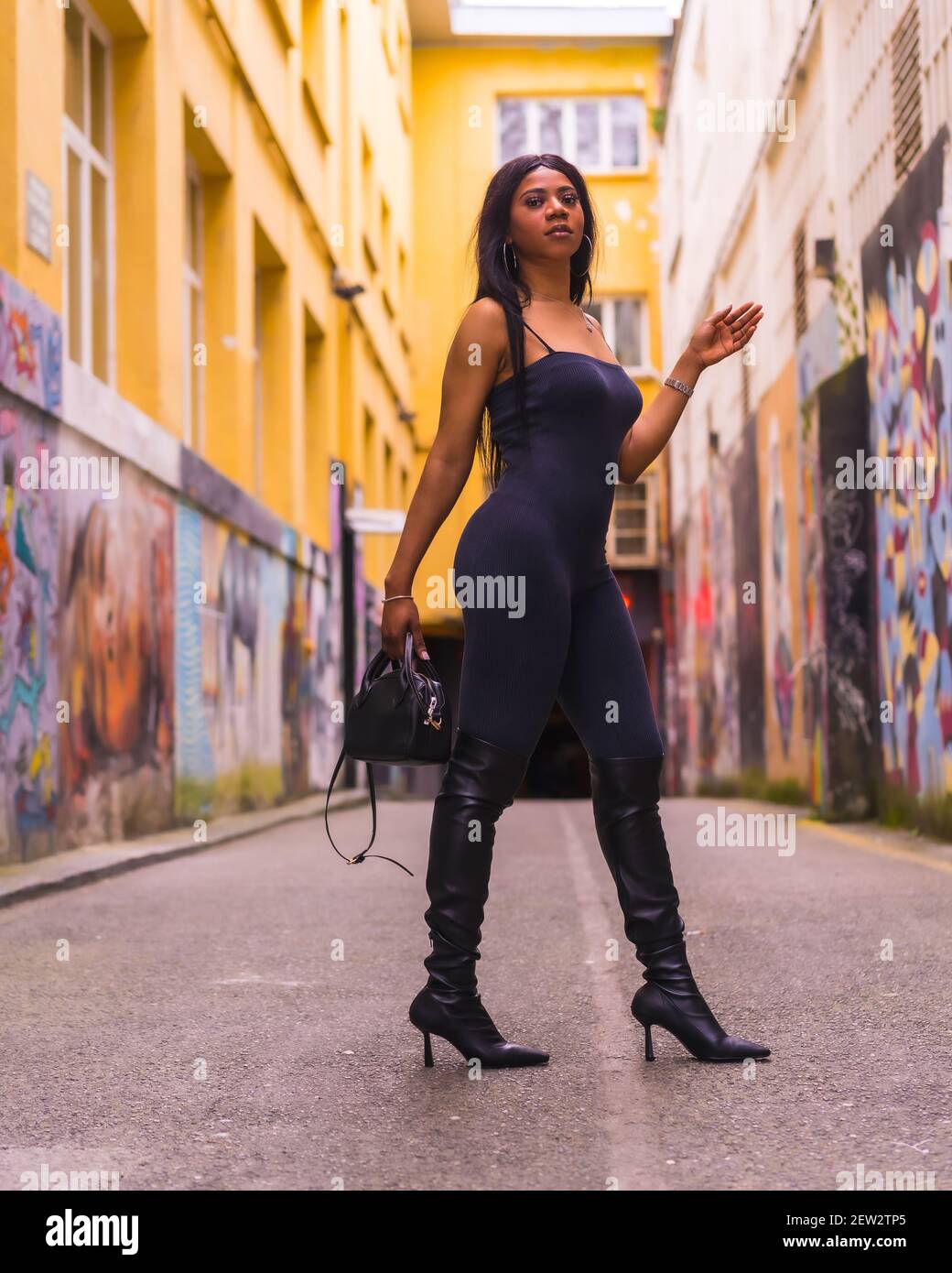 A vertical shot of a fashionable African American female model in a black top pants and high boots walking in a street Stock Photo Alamy