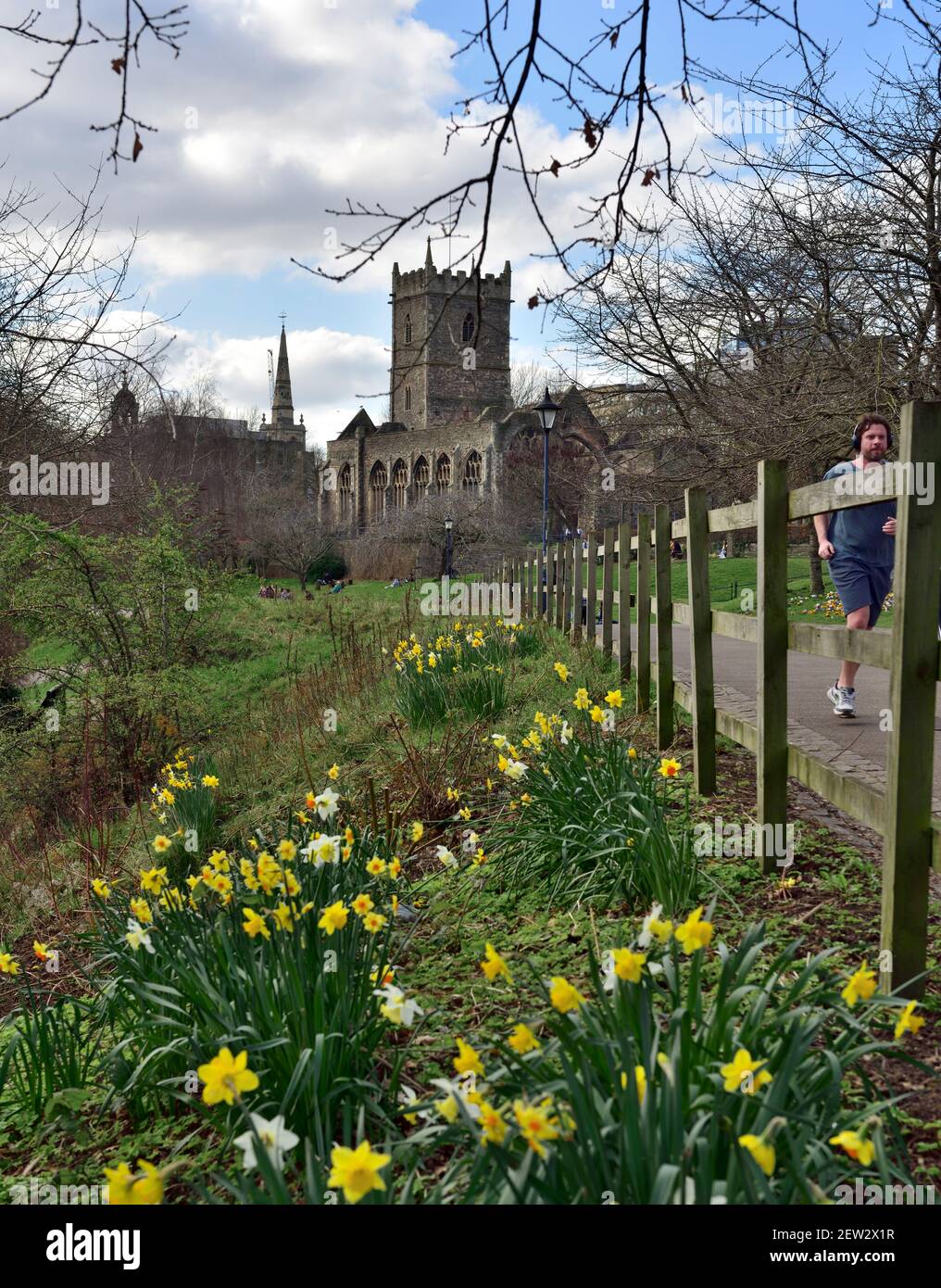Bristol Castle Park and Historic St Peter's Church winter day almost spring daffodils, jogging on path, UK Stock Photo