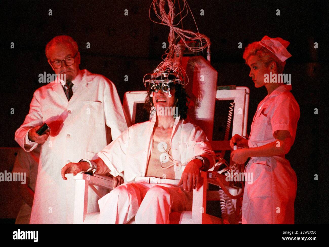 undergoing aversion therapy - l-r: Russell Enoch (Dr Brodsky), Phil Daniels (Alex), Natalie Roles (The Nurse) in A CLOCKWORK ORANGE 2004 at the Royalty Theatre, London WC2  26/05/1990  a Royal Shakespeare Company production  written by Anthony Burgess in collaboration with Ron Daniels  music by The Edge & Bono  design: Richard Hudson  lighting: David Hersey  choreography: Arlene Phillips  fights: Malcolm Ranson  director: Ron Daniels Stock Photo