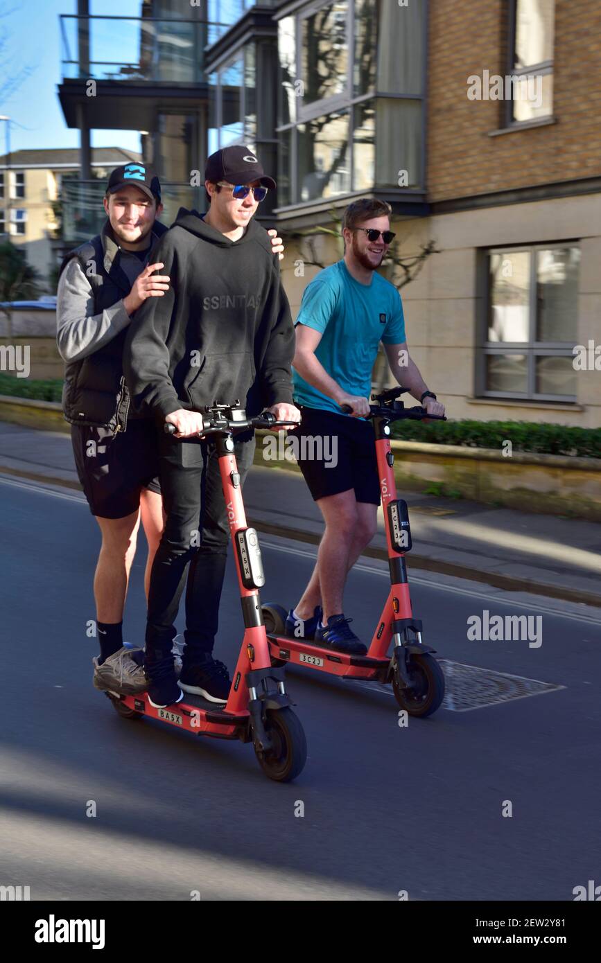 Three young men on two electric hire scooters Stock Photo Alamy