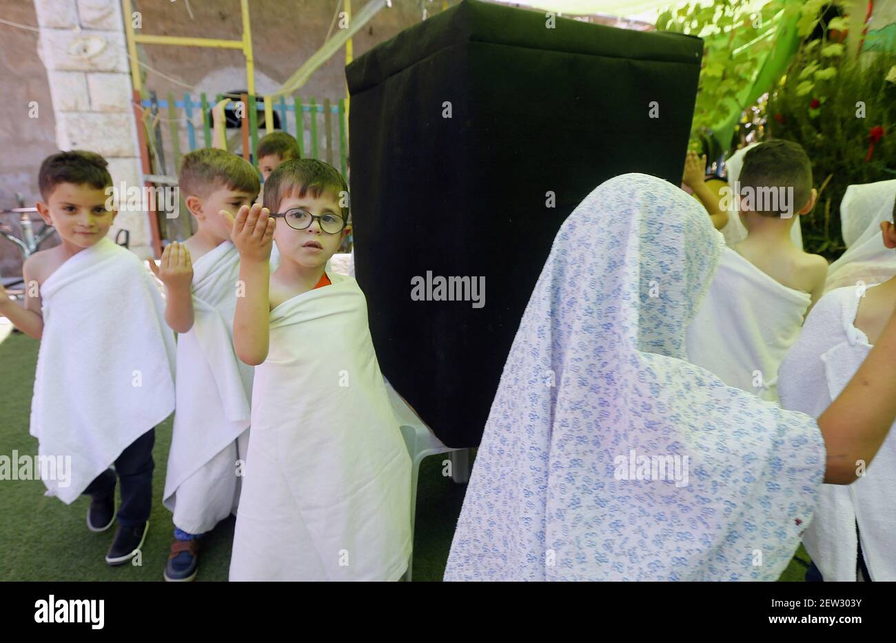 Palestinian children gather around a makeshift cube representing the