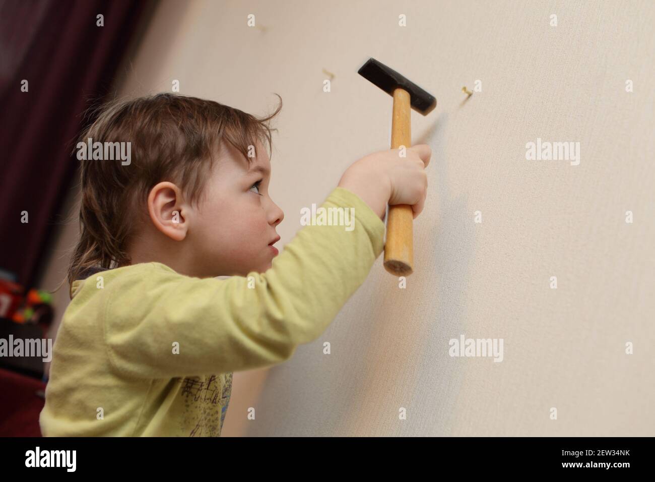 Kid hammering plastic anchor into wall at home Stock Photo - Alamy