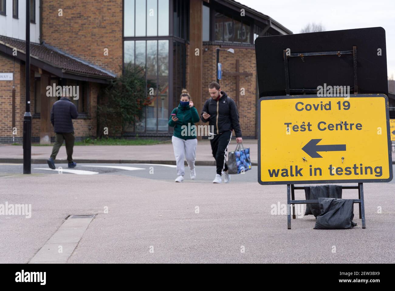 shoppers walk past road sign for covid-19 test centre offering walk-in testing service Stock Photo