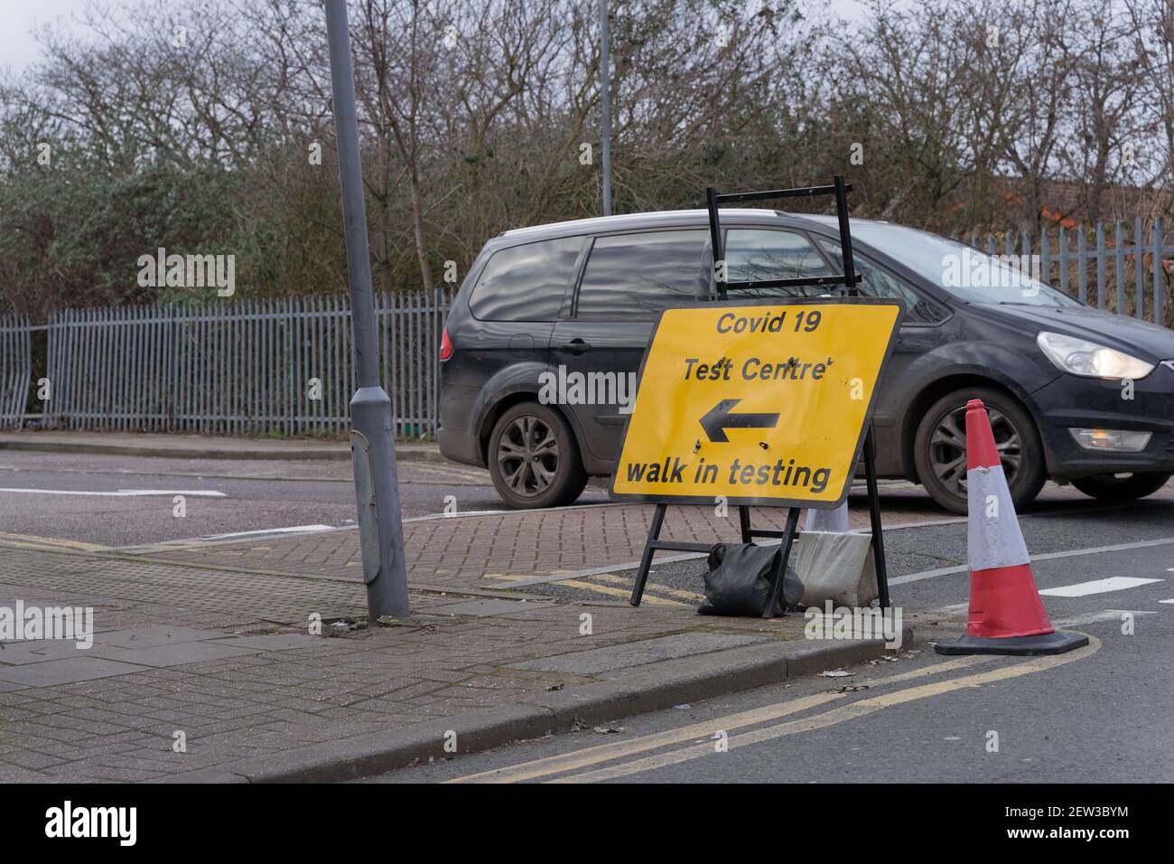 a car stops at give way junction where a road sign of covid 19 test centre is place on road side Stock Photo