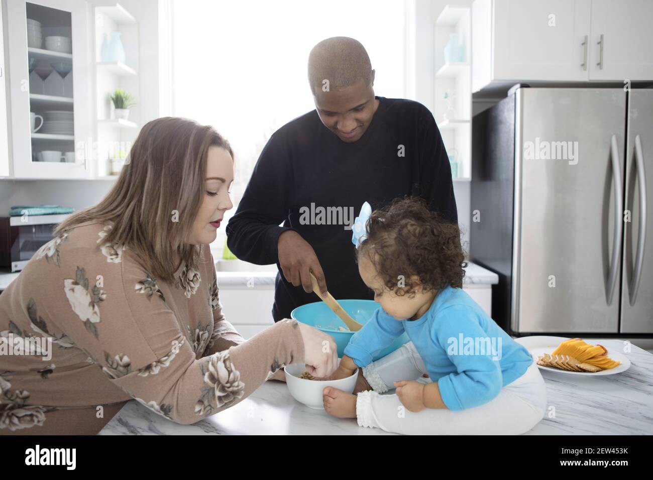 A young interracial family cooking together in a modern kitchen. Stock Photo