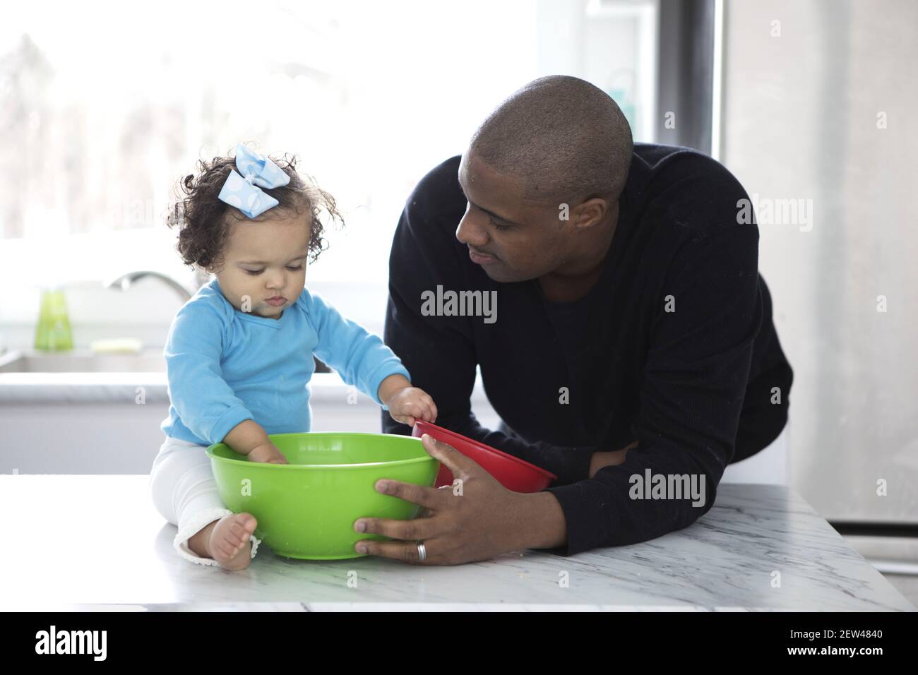 A Dad spends time in the kithchen with his daughter. They are baking, Stock Photo