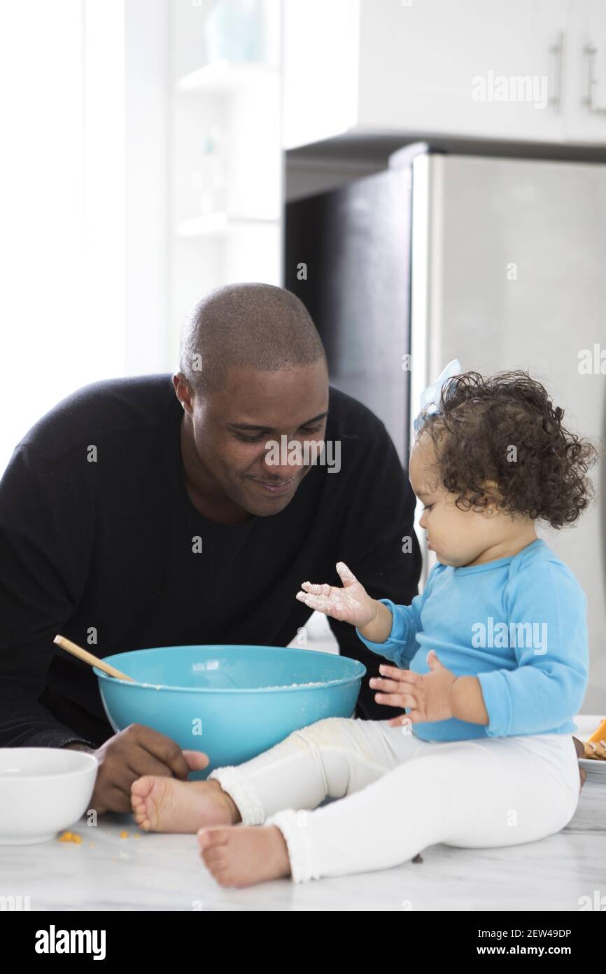 A Dad spends time in the kitchen with his daughter. They are baking, Stock Photo