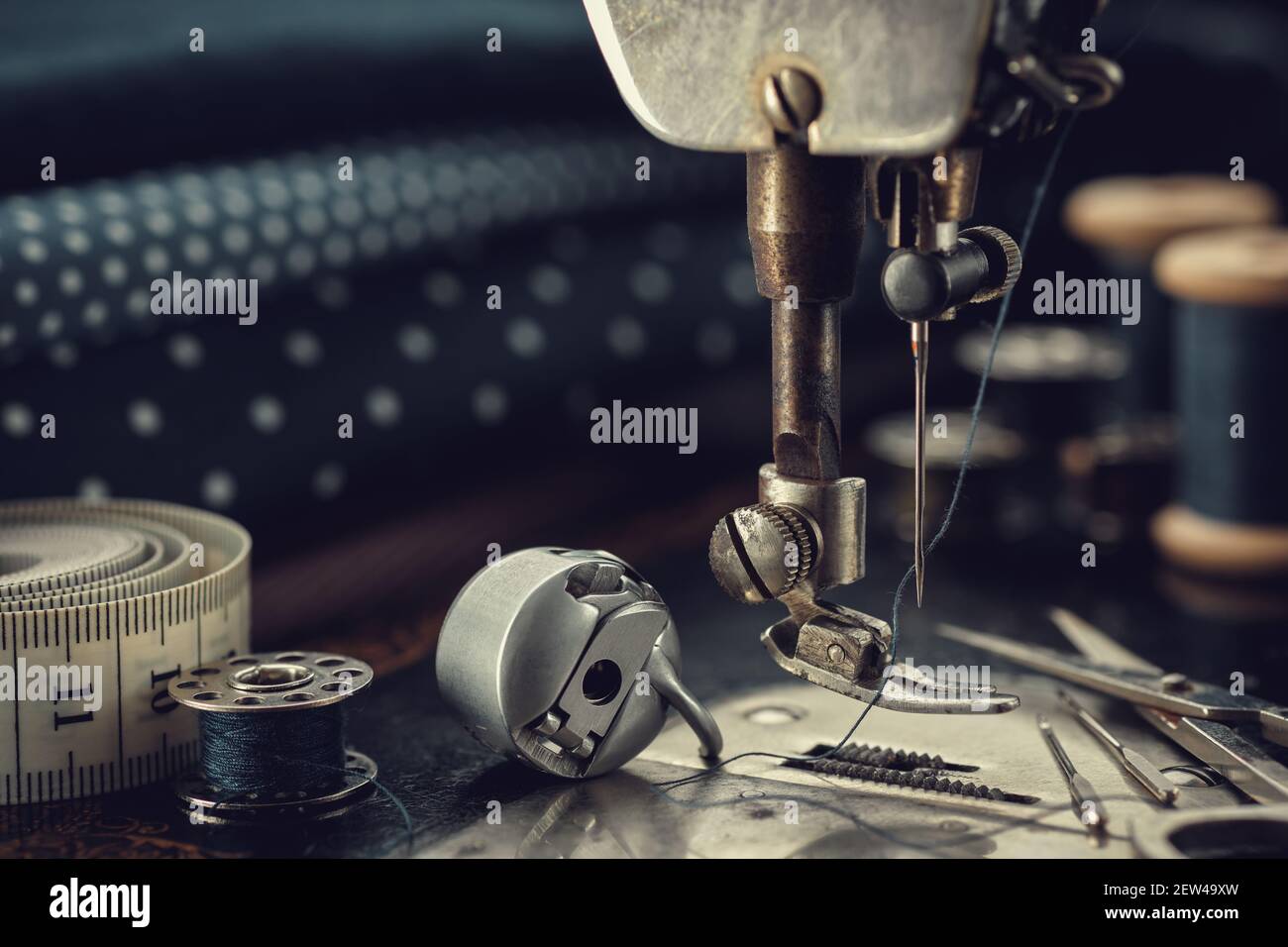 Working part of antique sewing machine with spools of threads, shuttle, measuring tape, sewing