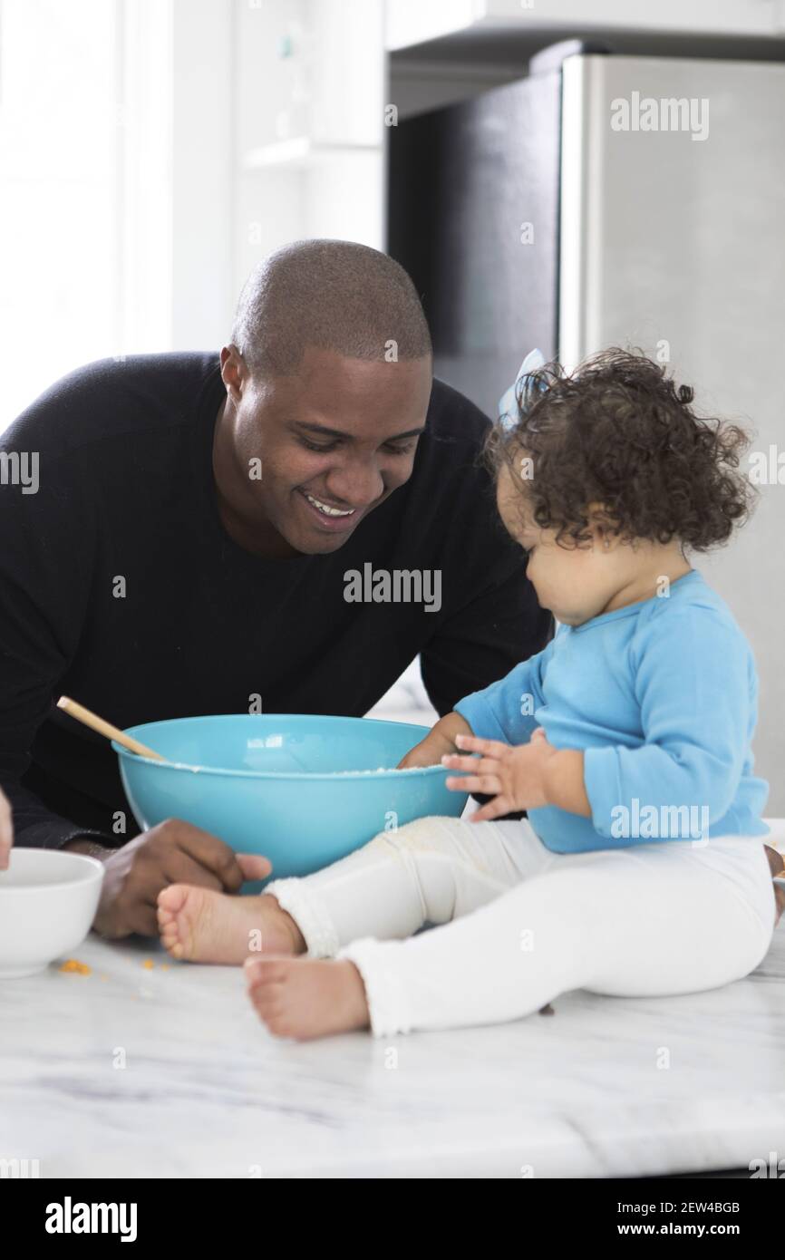 A Dad spends time in the kitchen with his daughter. They are baking, Stock Photo