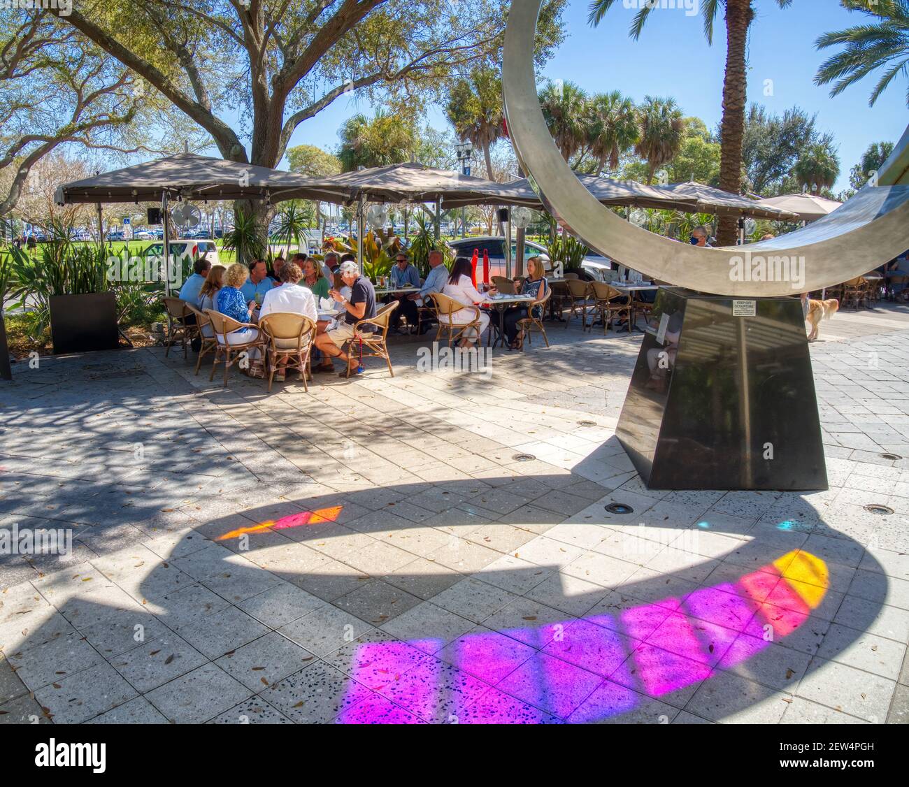 Colorful artwork and people eating at an outdoor cafe on the sidewalk on Beach Drive NE in St Petersbutg Florida USA Stock Photo