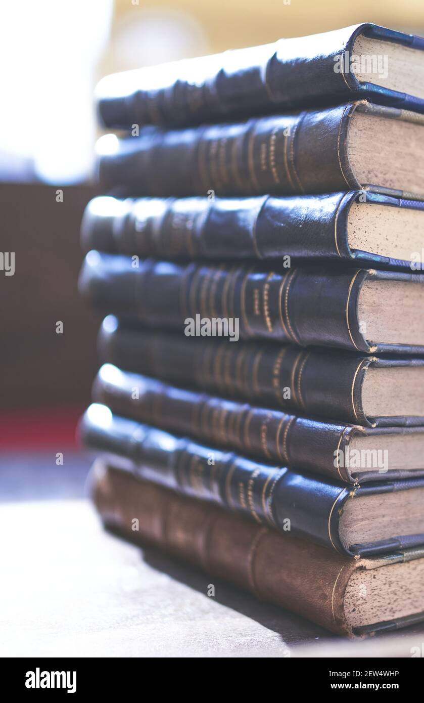 several old and slightly worn books stacked in a tower on a desk Stock Photo