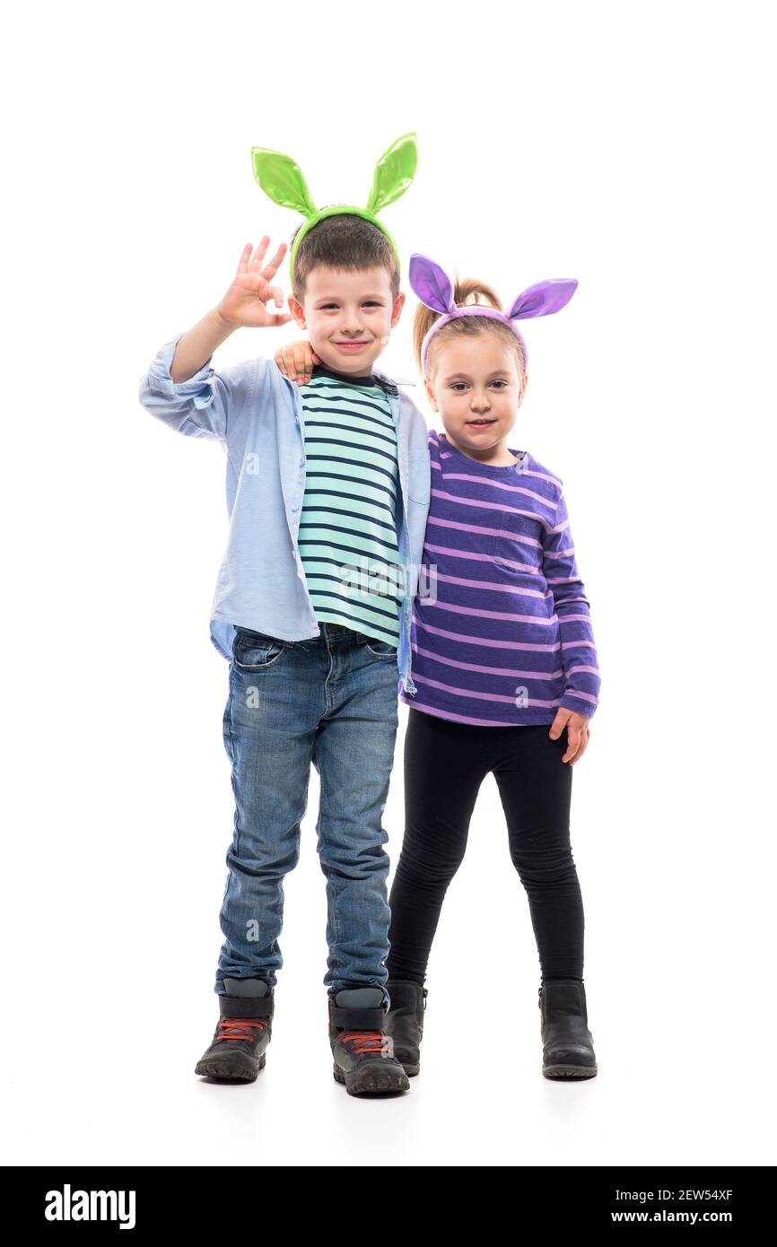 Adorable little boy and toddler cute girl hugging and waving hand at camera with Easter bunny ears. Full body isolated on white background. Stock Photo