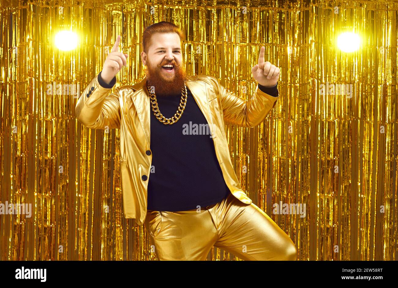 Rich chubby man in a golden suit dances at a party or disco on a bright shiny background. Stock Photo