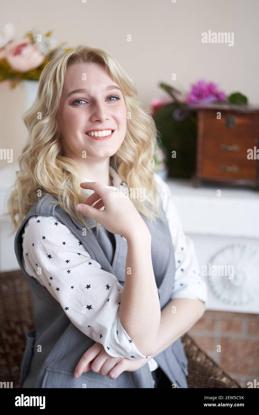Beautiful blonde specialist sits at a table and smiles, a woman looks into the frame Stock Photo