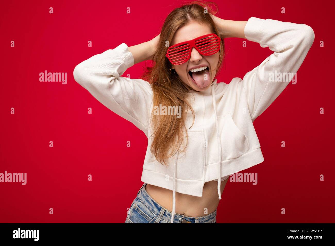 Photo shot of beautiful positive young blonde woman wearing casual clothes and stylish optical glasses isolated over colorful background wall looking Stock Photo