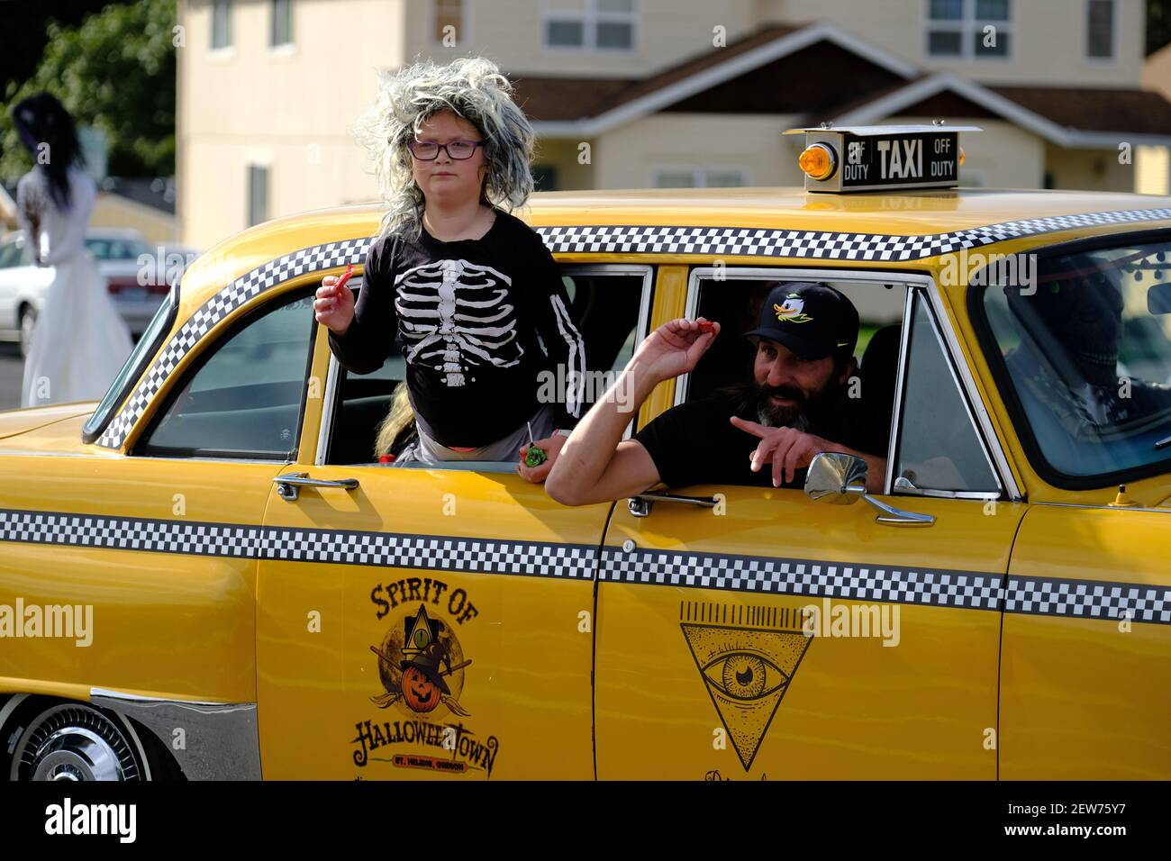 People throw candy from a taxi at the Spirit of Halloweentown parade in