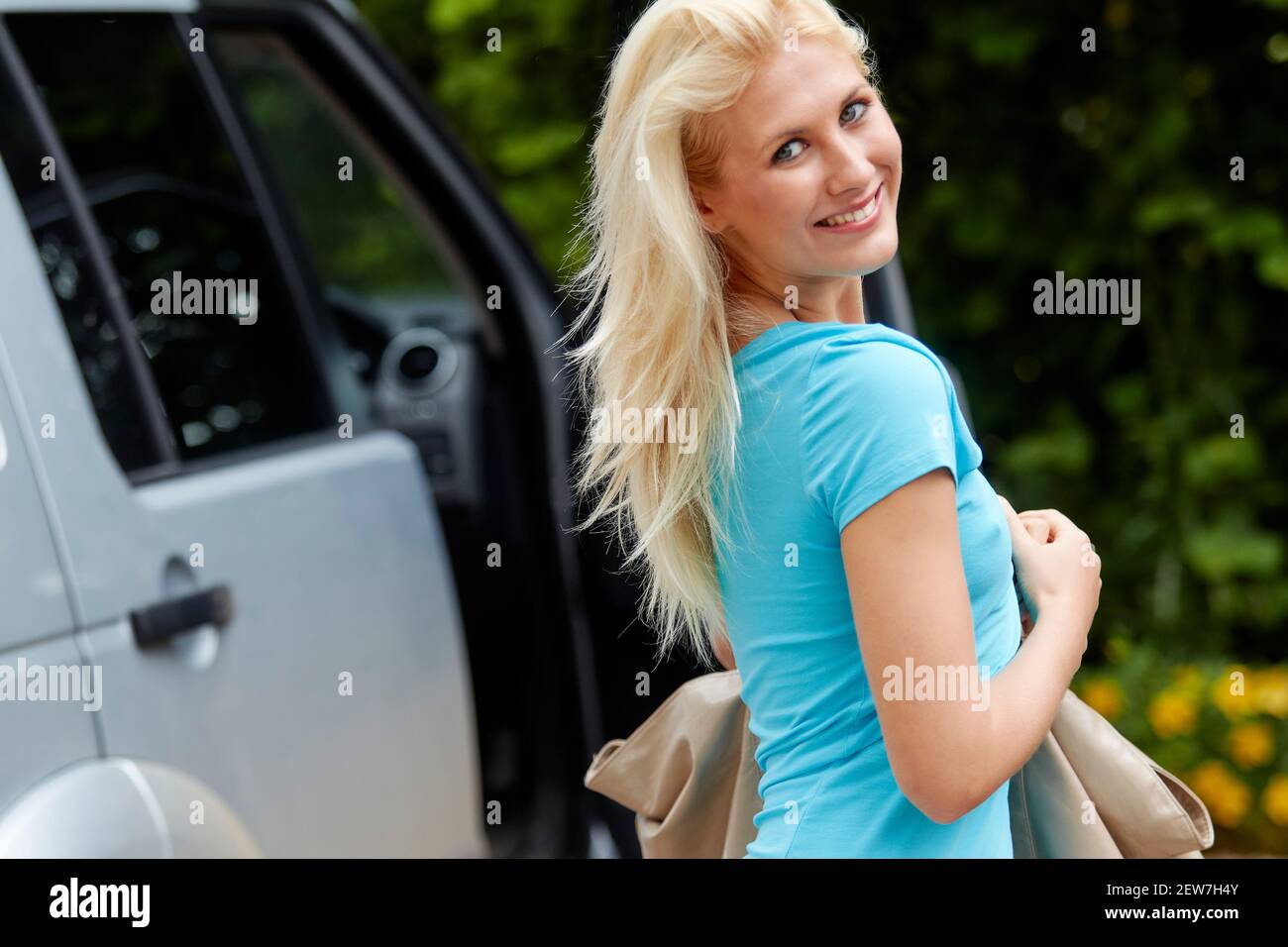 Beautiful girl with a bag getting into her car Stock Photo