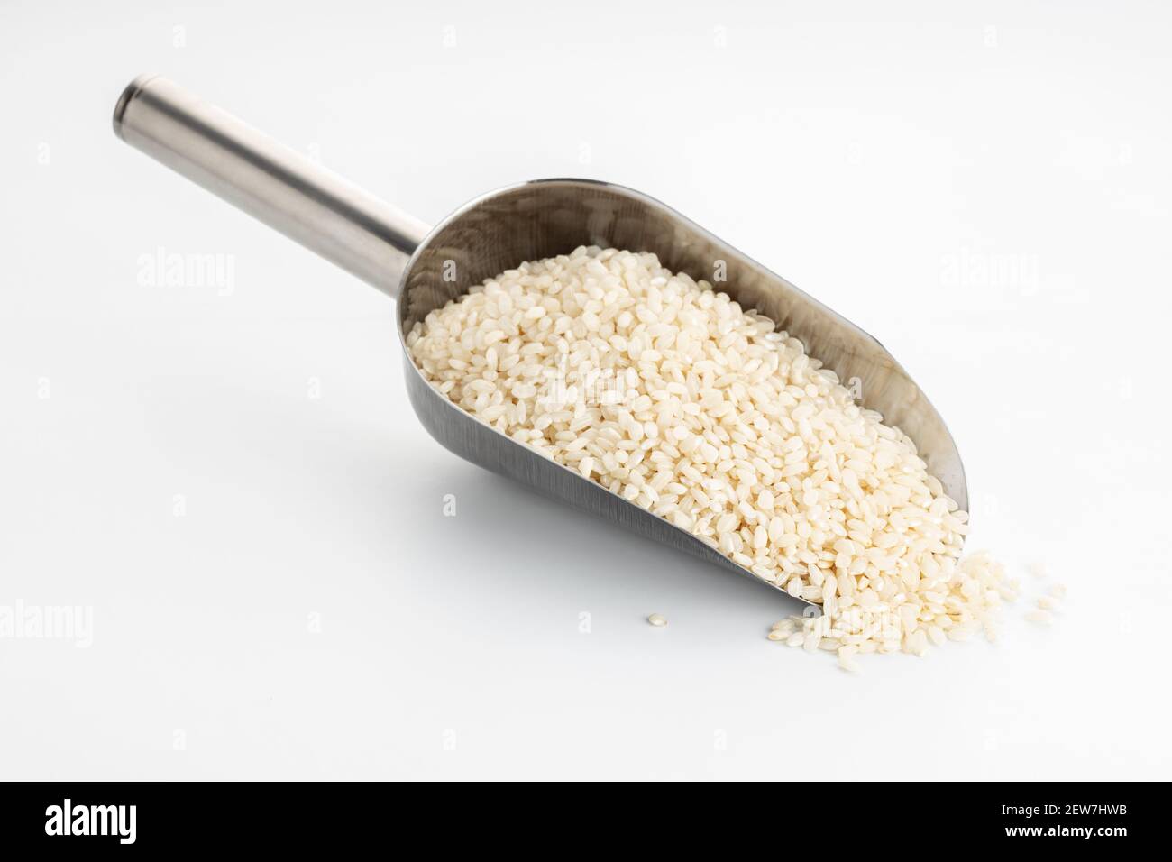 Raw rice on metallic scoop isolated on White table. Cereal grain Stock ...