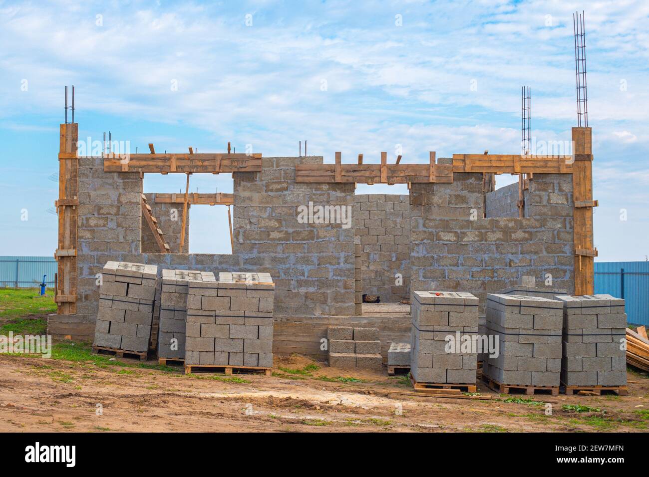 Construction stages. Cinder block country house with protruding fittings, ground floor. The building material is stacked on pallets. Stock Photo