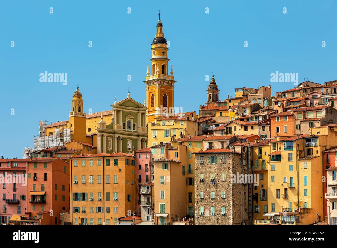View of colorful houses and belfry of the Saint Michel Archange basilica under blue sky in Menton - small town on French Riviera. Stock Photo