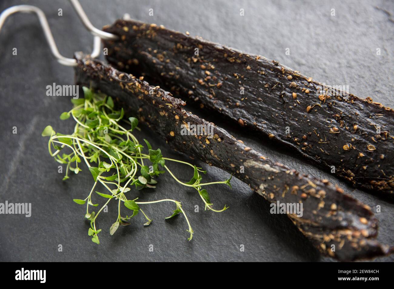 Venison from a wild fallow deer that has been hung on hooks to air dry to make homemade biltong. It was cured with salt, brown sugar and malt vinegar Stock Photo