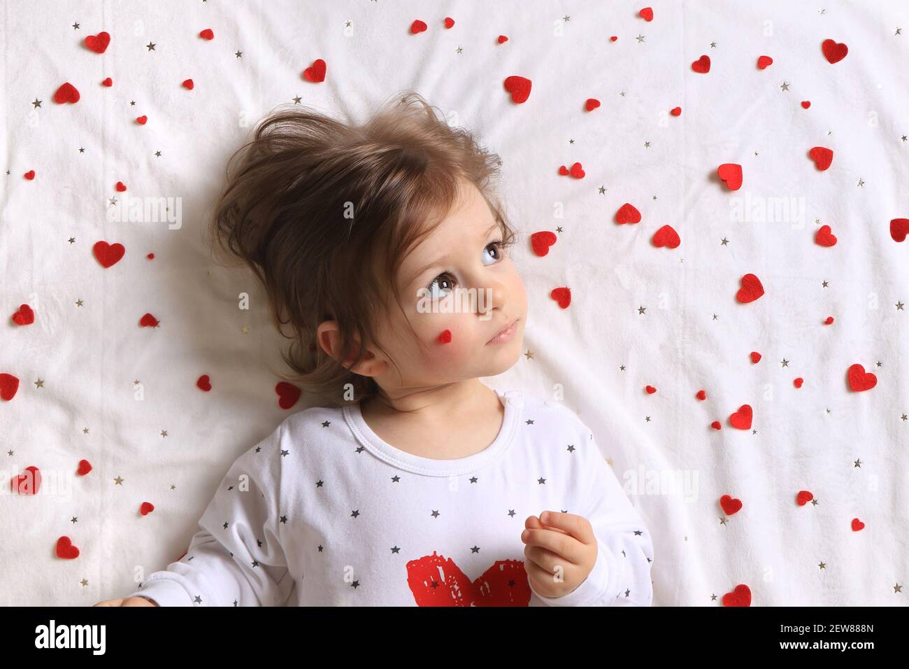 A toddler with lots of red hearts surrounding him on white. Stock Photo