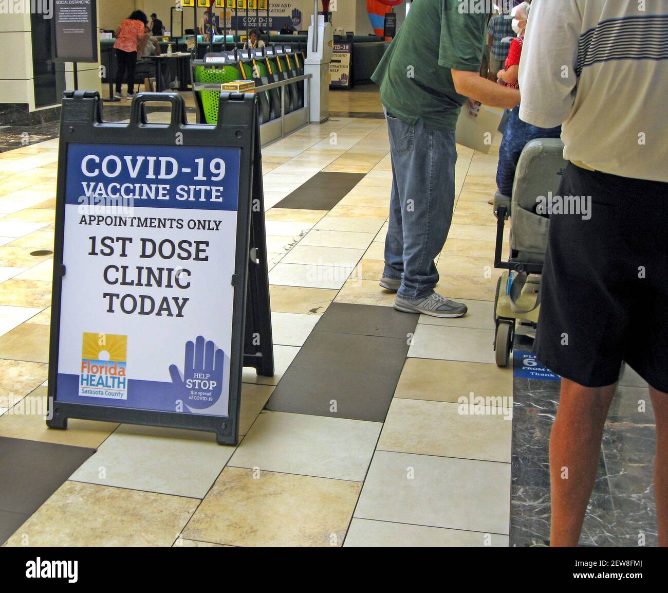 American seniors age 65 or older line up in a shopping mall during the initial wave of Covid-19 coronavirus vaccinations organized by the Department of Health of Sarasota County on the west coast of Florida, USA. Appointments made online or by telephone were required for the 1st dose of the two-shot Moderna vaccine, which also required a 2nd dose four weeks later. The county health department had injected doses of the vaccine into the upper arms of more than 50,000 people by March, 2021, one year after this global pandemic was declared by the World Health Organization (WHO). Stock Photo