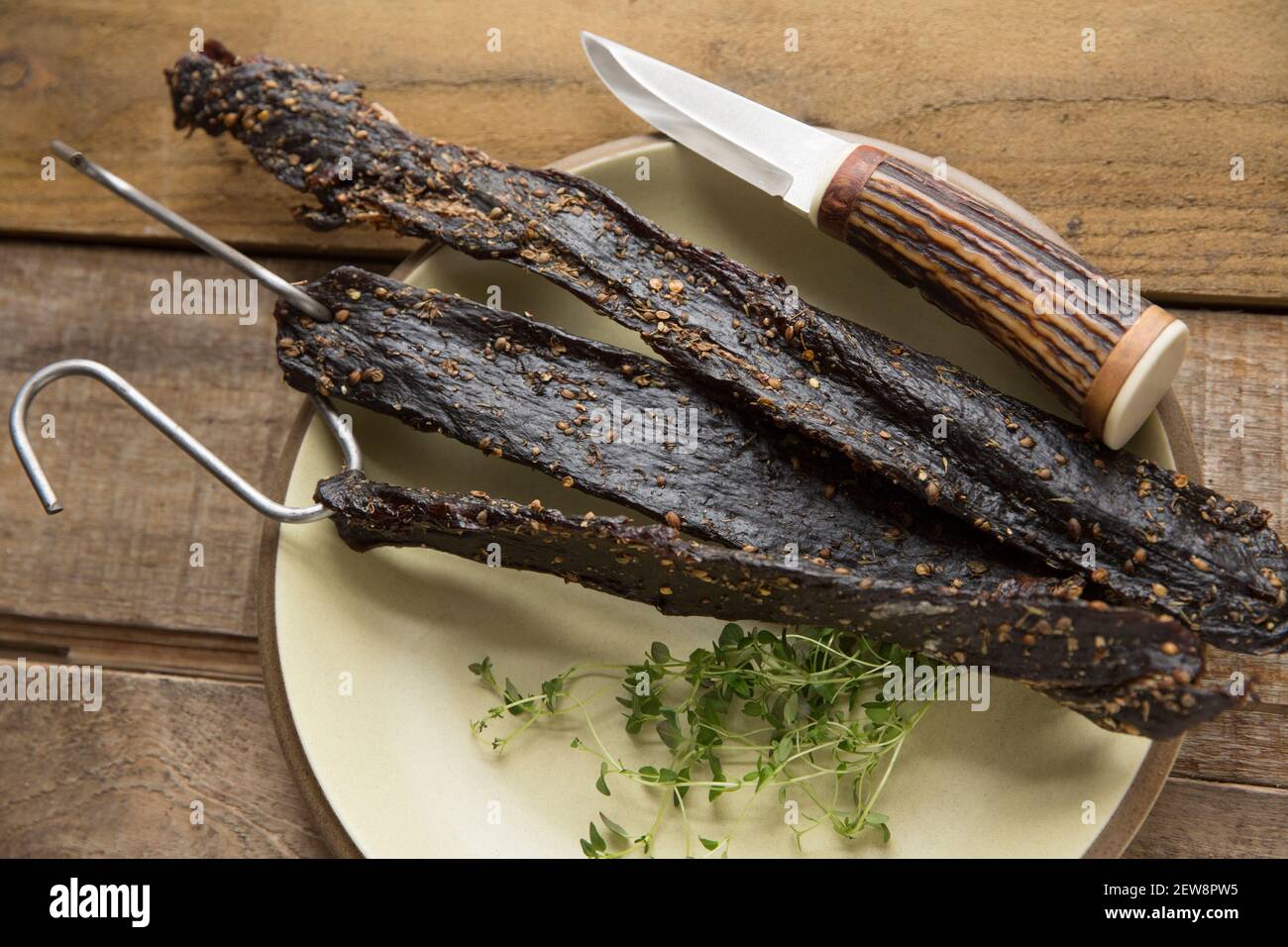 Venison from a wild fallow deer that has been hung on hooks to air dry to make homemade biltong. It was cured with salt, brown sugar and malt vinegar Stock Photo