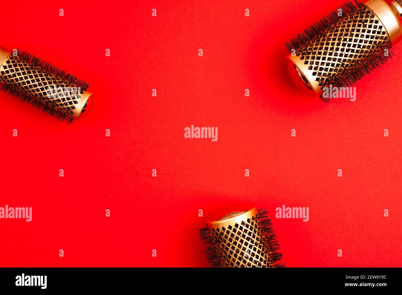 Flat lay from above set of professional gold round hair brushes for styling template with copy space on red background. Hairdresser salon equipment co Stock Photo