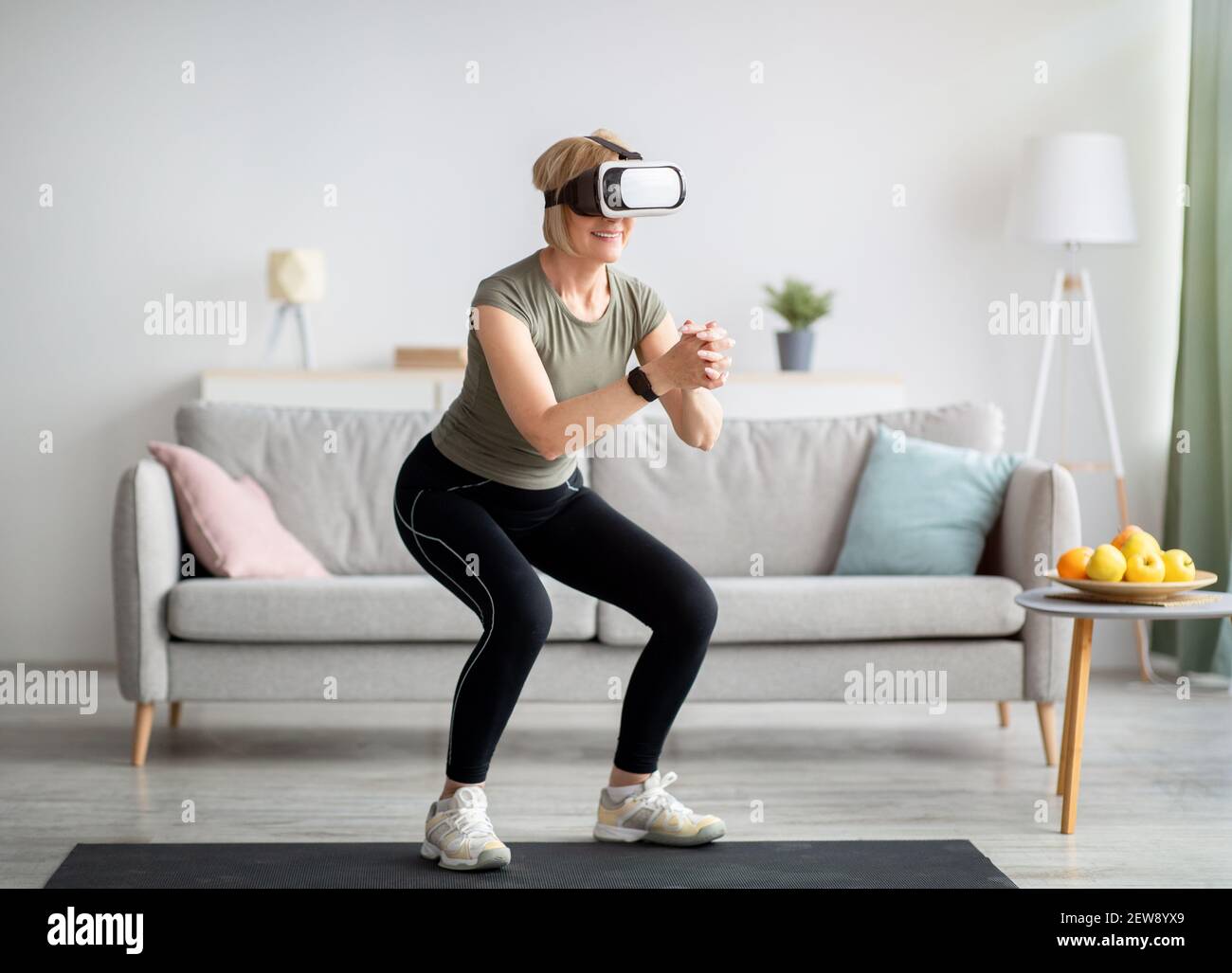 Exercising with virtual reality concept. Athletic mature woman in VR