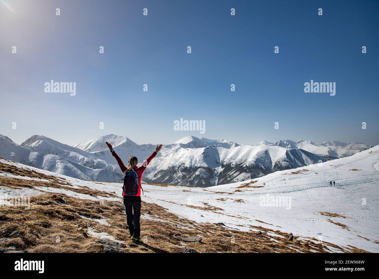 Back view of woman hiker in warm clothing with backpack standing with ...