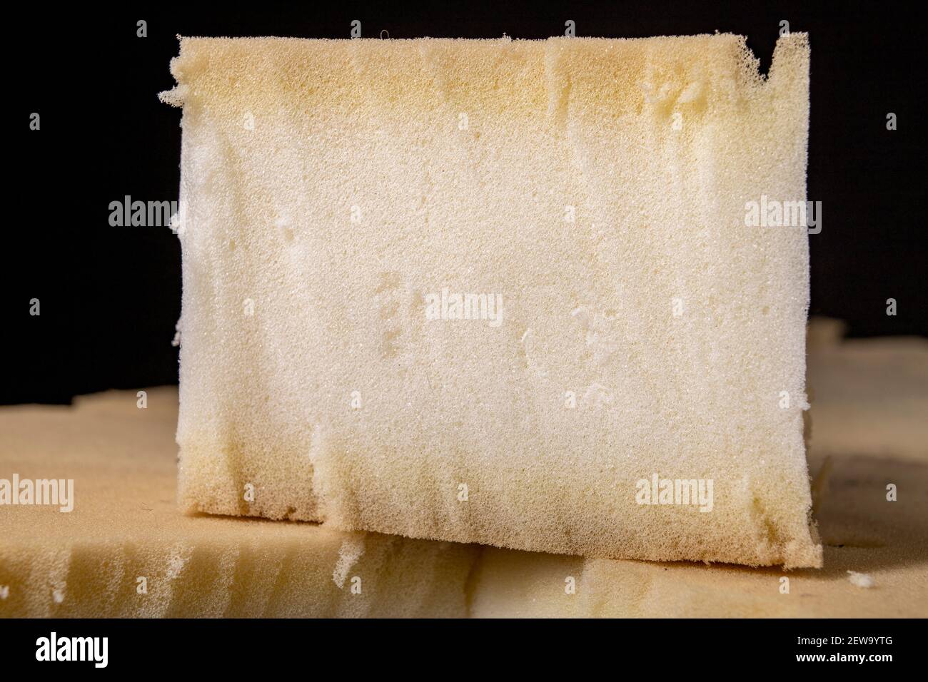 A cut sponge in an upholstery workshop. The material used to build soft sofas and armchairs. Dark background. Stock Photo