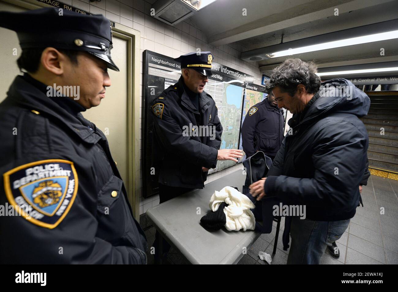 NYPD officers stop a man to check his bag before he enters the 81st MTA