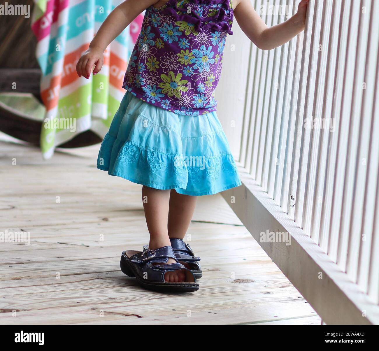 Young caucasian toddler girl trying on her mother's shoes while vacationing at a beach house in The Outer Banks Stock Photo