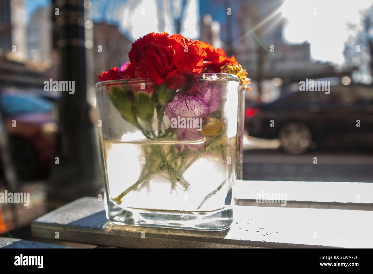 A glass vase with red roses and colorful flowers displayed on a table