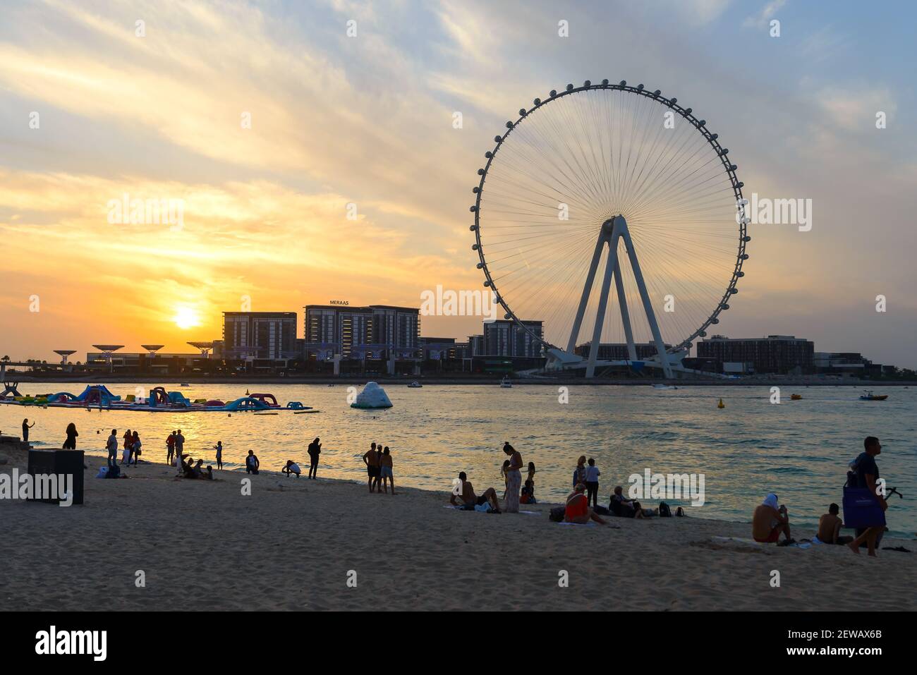 Tourists at JBR Marina Beach during sunset and Ain Dubai Eye ferris wheel silhouette. United Arab Emirates is open for tourism with COVID restrictions. Stock Photo