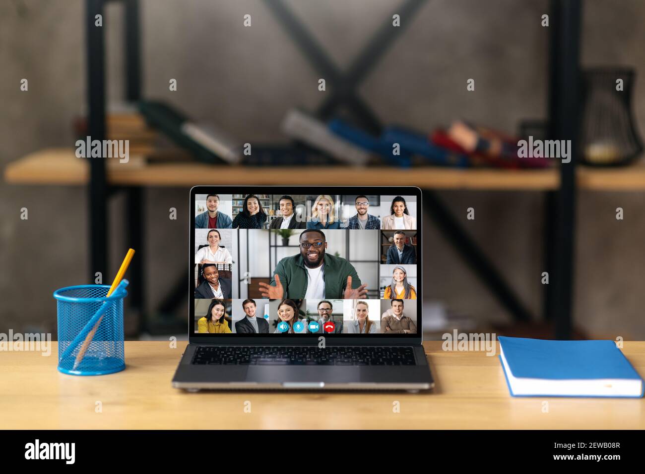 Online business briefing, brainstorm. A laptop stands on the desktop, on the laptop screen is many different multiracial coworkers, gathered, communication, solving working issues Stock Photo
