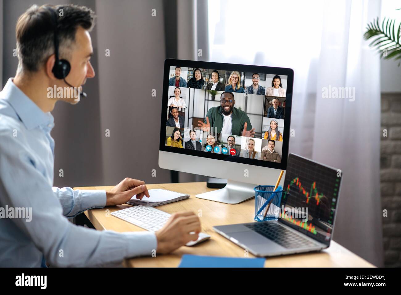 Business meeting online. Successful businessman is negotiating with multiracial business partners on a video conference using a computer while sitting at his workplace Stock Photo