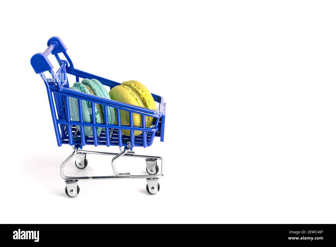 Blue and yellow macarons lie in metal shopping cart isolated on white background Stock Photo