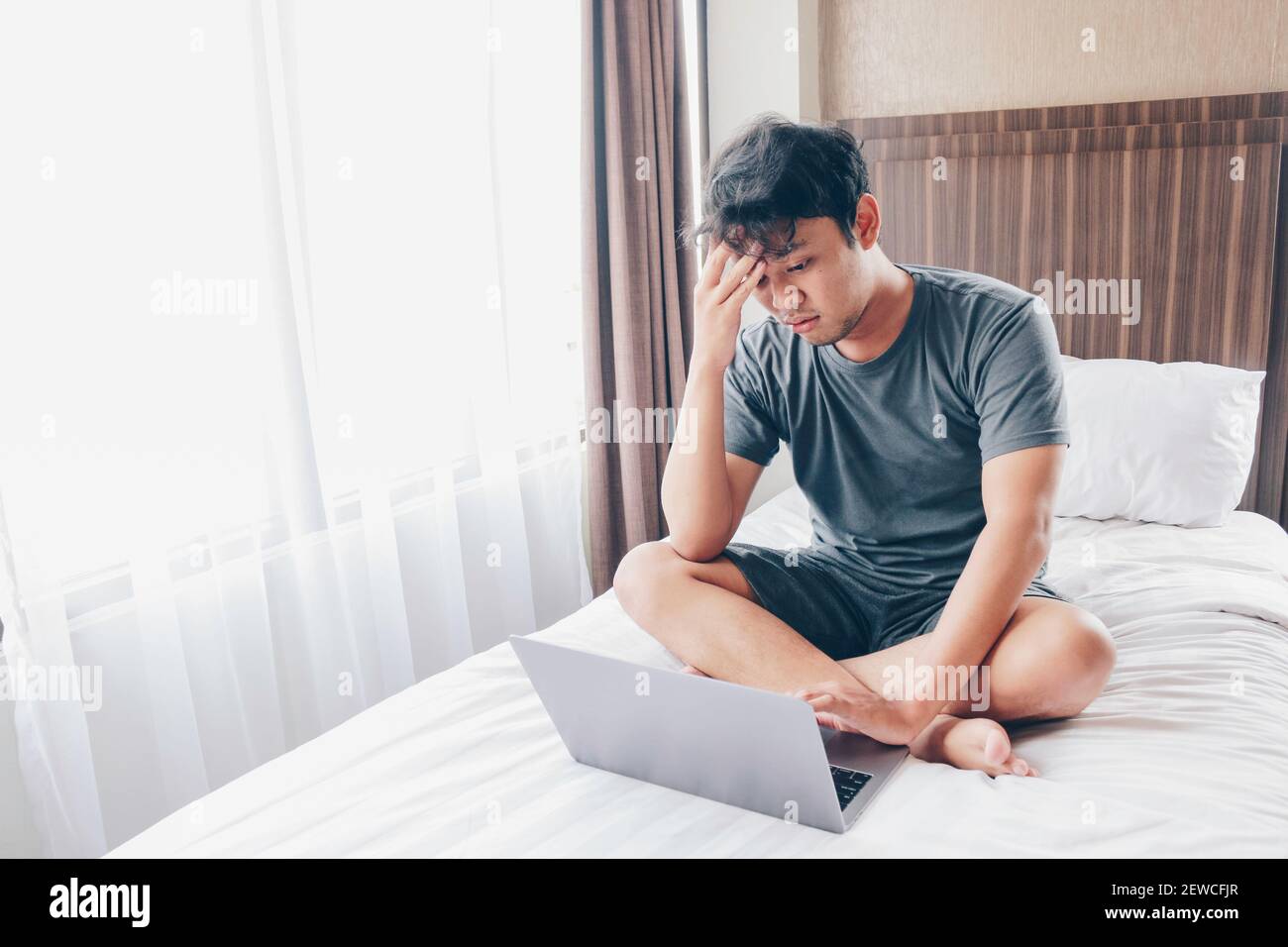 Tired stressed young Asian man feeling sleepy and tired while using