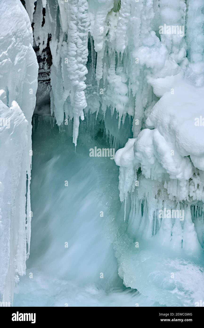 A vertical image of The Athabasca falls in winter with frozen icicles clinging to the rock canyon walls in Jasper National Park in Alberta Canada. Stock Photo