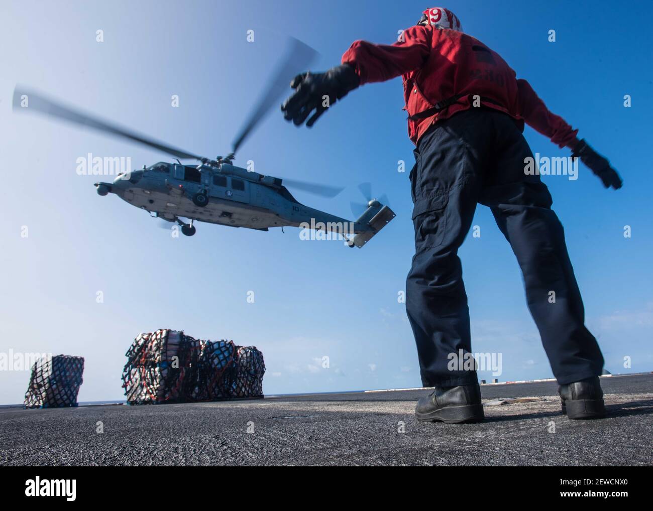 Aviation Ordnanceman Airman Kersan Sorendo directs an MH-60S Sea Hawk assigned to the Chargers of Helicopter Sea Combat Squadron (HSC) 14 during an replenishment-at-sea with USNS Henry J. Kaiser (T-AO 187) on USS John C. Stennis' (CVN 74) flight deck. Stock Photo