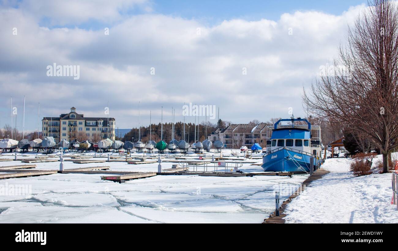 Thornbury, Ontario, Canada - 02-27-2021: The Huronic, a Collingwood Charter cruising and sightseeing boat is docked at the Thornbury Harbour to overwi Stock Photo